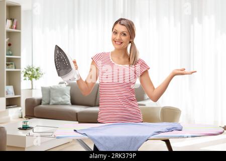 Smiling woman posing with an iron at home in a living room Stock Photo