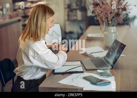 Woman analyst working with documents during video conference while sitting in modern coworking Stock Photo