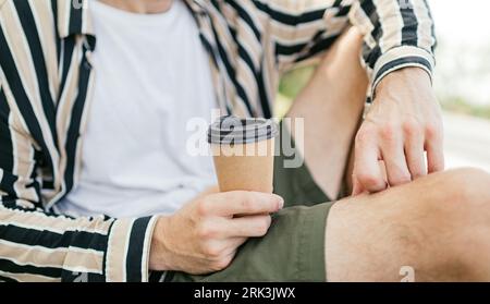 Paper cup with black lid in man's hand. Close Up, coffee cup, mockup. take away concept. Stock Photo