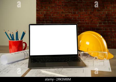 architect engineers Working on a desktop computer on a laptop mockup screen with an architectural project and blueprint on a desk working equipment in Stock Photo
