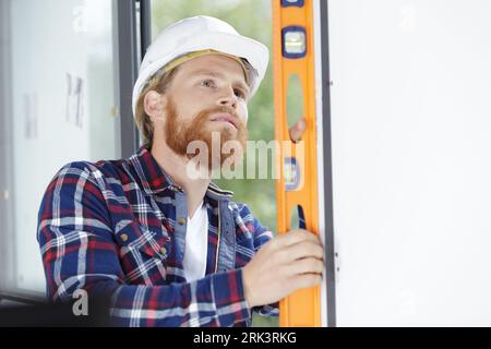 builder man checking vertical surface with bubble level Stock Photo