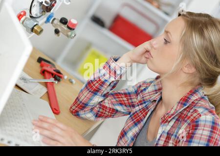 female technician servicing a boiler using computer Stock Photo