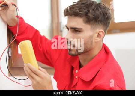 electrician measuring voltage of socket in new building Stock Photo