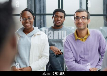 smiling man and woman talking while sitting on chairs Stock Photo