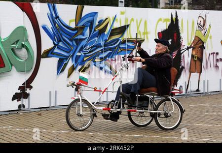 Bildnummer: 53588297  Datum: 09.11.2009  Copyright: imago/Xinhua  An old man rides a tricycle in front of graffiti drawn on an art installation symbolising parts of the Berlin Wall in central Sofia Nov. 9, 2009. The art project, called The Wall 20 , marks the 20th anniversary of the fall of the Berlin Wall and the Iron Curtain in Europe. (Xinhua/Velko Angelov) (lyi) (1)BULGARIA-SOFIA-BERLIN WALL-COMMEMORATION PUBLICATIONxNOTxINxCHN 20 Jahre Mauerfall Jahrestag Kunst Kunstprojekt kbdig xsk 2009 quer    Bildnummer 53588297 Date 09 11 2009 Copyright Imago XINHUA to Old Man Rides a Tricycle in Fro Stock Photo