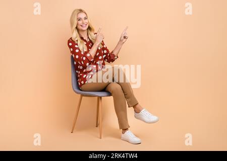 Full size body cadre of young businesswoman indicate fingers empty space new product placement promoter isolated on beige color background Stock Photo