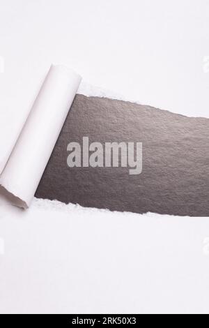 Torn paper with opening showing black background Stock Photo