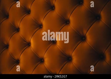 A closeup shot of a brown leather upholstered cushion surface Stock Photo