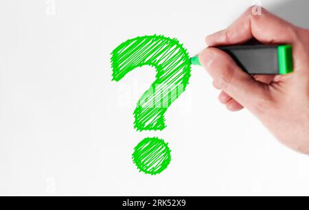 Customer questions and client faqs concept top view close up of a man hand drawing a green question mark sign icon on white background with copy space Stock Photo