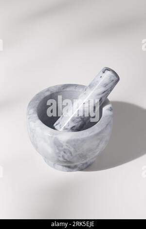 A white stone mortar on a white wooden table. Stock Photo