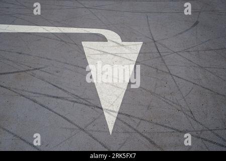 White painted arrow on a road surface, pointing down Stock Photo