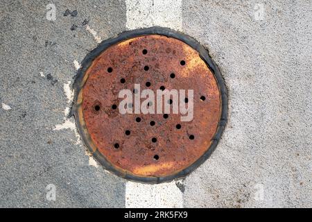 rusty drain cover in road surface, top down view. Stock Photo