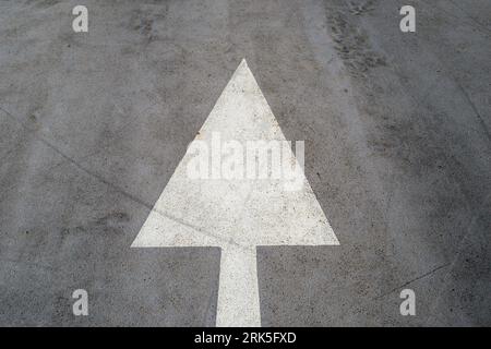 White painted arrow on a road suface, straight ahead. Stock Photo