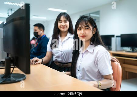 Two Asian female students sitting side by side in front of a computer Stock Photo