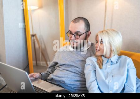 Young man and woman spend time together using laptop. Couple making online shopping purchases. Stock Photo
