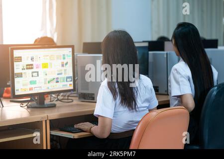 Two East Asian females in a professional office setting using a computer monitor for work Stock Photo