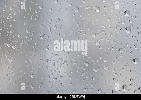 Closeup shot of rain droplets forming on the glass window pane Stock Photo