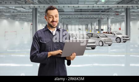 Car mechanic using a laptop computer inside a garage Stock Photo