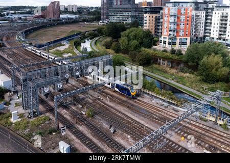 An aerial view of a passenger train travelling through a major rail junction with overhead gantry signals that have been annotated with letters to hel Stock Photo