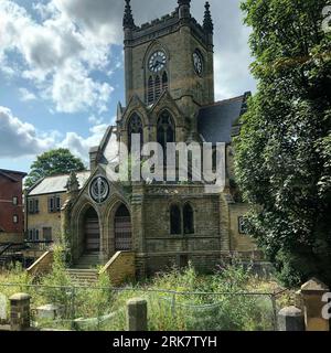 A traditional old church with a clock tower surrounded by lush greenery Stock Photo