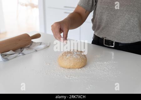 a young woman placing flour to homemade dough Stock Photo