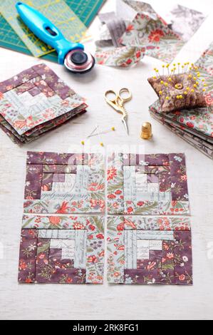 Patchwork log cabin blocks, stack of blocks, sewing accessories on white wooden surface Stock Photo