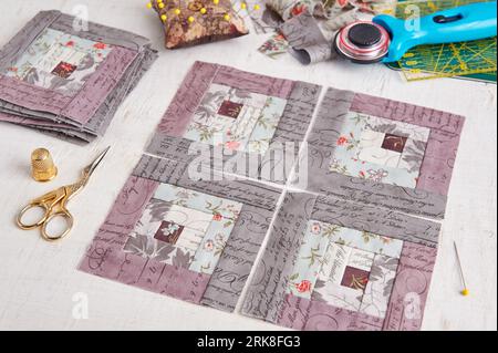 Patchwork log cabin blocks, stack of blocks, sewing accessories on white wooden surface Stock Photo