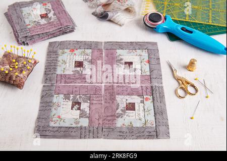 Patchwork log cabin blocks, stack of blocks, sewing accessories on white wooden surface Stock Photo