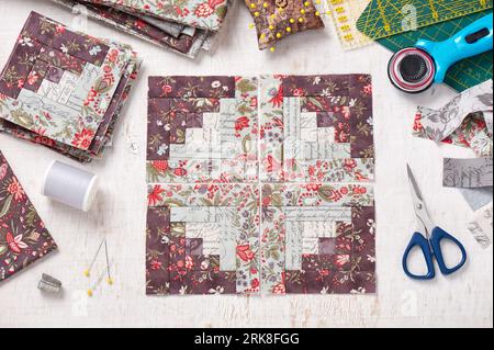 Patchwork log cabin blocks, stack of blocks, sewing accessories on white wooden surface Stock Photo
