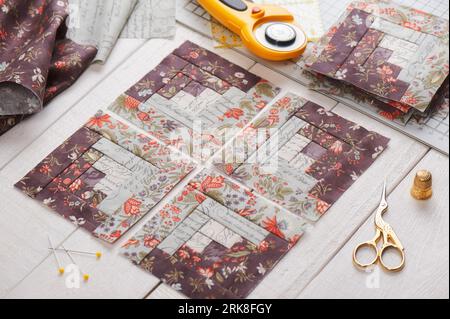 Patchwork log cabin blocks, stack of blocks, sewing accessories on white wooden surface Stock Photo