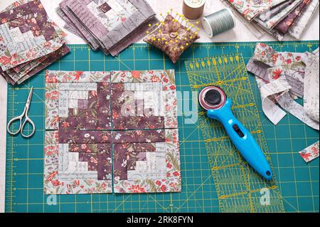 Patchwork log cabin blocks on craft mat, stack of blocks, sewing accessories Stock Photo