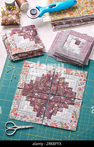 Patchwork log cabin blocks on craft mat, stack of blocks, sewing accessories Stock Photo