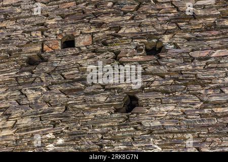 A close-up view of the façade of a fortified tower in Shatili, Khevsureti, Georgia. The small rectangular openings served as loopholes; the masonry, consisting of flat layers of slate slabs in various shades of brown and grey, is characteristic of the medieval building tradition of the high-mountain regions of the Greater Caucasus. Shatili, Dusheti Municipality, Mtskheta-Mtianeti, 1800, Georgia Stock Photo