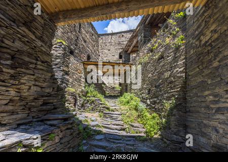 A view through a covered passageway onto an inner courtyard with slate-stone steps in the fortified village of Shatili, Khevsureti, Georgia. Wooden bridgeways in the background connected the individual buildings to form a cohesive defensive complex, which, despite repeated sieges, was never conquered. 3rd Street, Shatili, Dusheti Municipality, Mtskheta-Mtianeti, 1800, Georgia Stock Photo