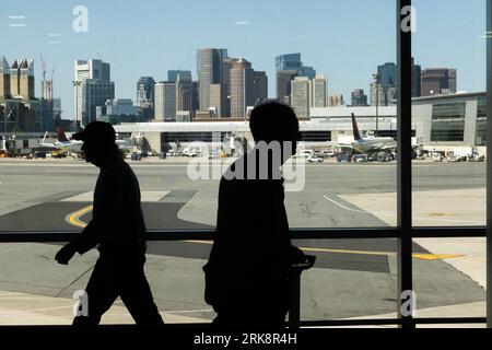 People are seen traveling through Logan International Airport on August 24, 2023. Airports remain busy with college students coming into the city amid late summer travel plans. A recent article in the New York Times exposed a pattern of close calls in airplane collisions across the United States. Stock Photo