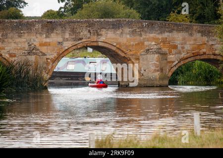 A canoeist passes under he picturesque bridge over the river Nene at Fotheringhay was built in 1722 and replaced an older bridge which was ordered built by Elizabeth I. Stock Photo