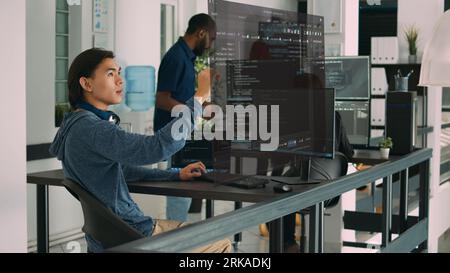 Qualified programmers helped by AR technology to visualize script in coworking space, writing code on computer using Java programming languages. Colleagues solving errors and reinforcing encryption Stock Photo