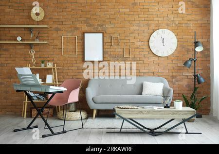 Interior of stylish living room with modern synthesizer and sofa against brick wall Stock Photo
