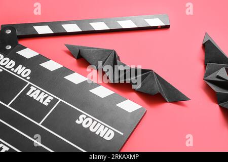 Composition with clapperboard and paper bats on red background. Halloween celebration Stock Photo