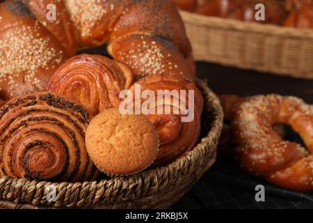 Wicker basket and different tasty freshly baked pastries on table, closeup Stock Photo