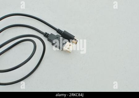 Black USB Type-C cable detail highlighted on a clear surface, perfect for modern technology concepts. Close-up black USB Type-C cable providing speed Stock Photo