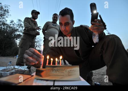 Bildnummer: 54710412  Datum: 05.12.2010  Copyright: imago/Xinhua (101205) -- HAIFA (ISRAEL), Dec. 5, 2010 (Xinhua) -- An Israeli Defence Force (IDF) soldier, who participates in the task of fire-fighting, lights candles to celebrate the fifth day of the eight-day Jewish Festival of Lights, named Hanukkah, near Haifa, north Israel, Dec. 5, 2010. After more than three days arduous battle, Israeli firefighting authority announced Sunday afternoon that it had fully contained the inferno, according to local news service Ynet. (Xinhua/Yin Dongxun) (wjd) ISRAEL-FOREST FIRE-CONTROL PUBLICATIONxNOTxINx Stock Photo