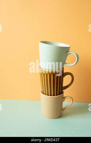 Stack of mug cup on mint green table. orange wall background. copy space Stock Photo