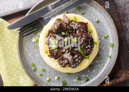 Portion of chicken liver with onions stewed in honey wine sauce with garnish mashed potatoes close-up in a plate on the table. Horizontal top view fro Stock Photo