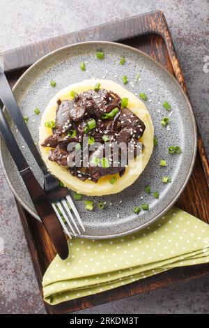 Chicken liver with onions stewed in honey wine sauce with garnish mashed potatoes close-up in a plate on the table. Vertical top view from above Stock Photo