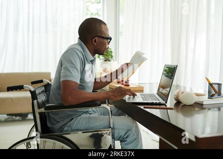 Man with disability checking his medical documents and filling form on website of clinic Stock Photo