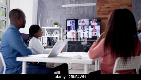 Group Of Businesspeople Having Video Conference With Another Business Team In Office Stock Photo