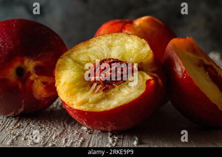 Broken nectarine on a rustic background. The fruits of summer. Three red nectarines. Stock Photo