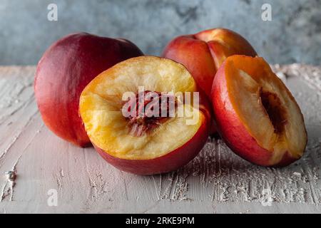 Broken nectarine on a rustic background. The fruits of summer. Three red nectarines. Stock Photo