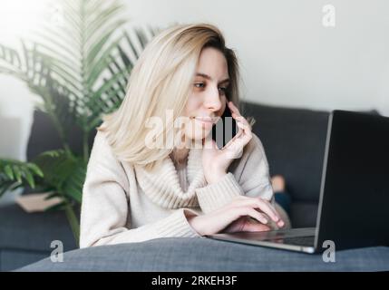Young woman  using laptop computer at home sitting comfortably  in living room. Stock Photo